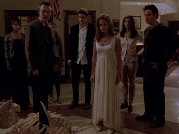 Jenny, Giles, Willow Angel, Buffy, Cordelia and Xander all stand together over the Master's bones.