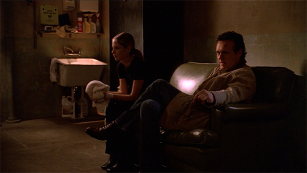 Buffy and Giles sit in the Magic Box training room.