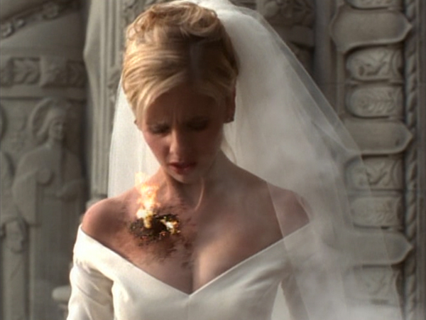 Buffy stands in a wedding dress, starting to catch fire.