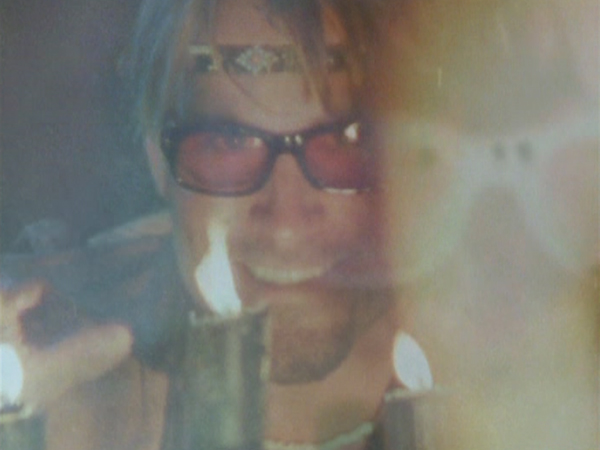 A 70s-looking man in sunglasses stares sinisterly into the camera.