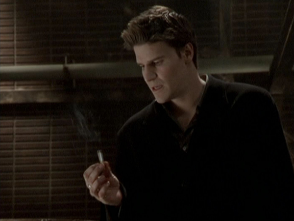 Angel sits and lights a cigarette.