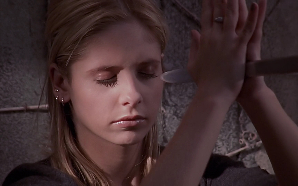 Buffy holds a sword blade between her hands, eyes closed