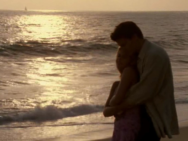 Buffy and Angel hold each other on a beach, in the setting sun.