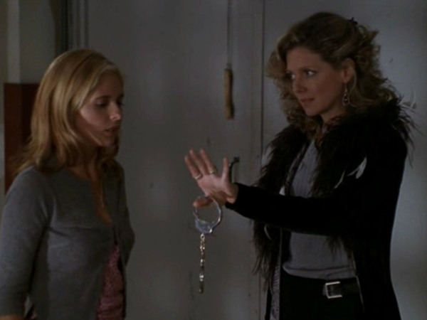 Joyce offers Buffy a pair of handcuffs, with an embarassed look on her face.