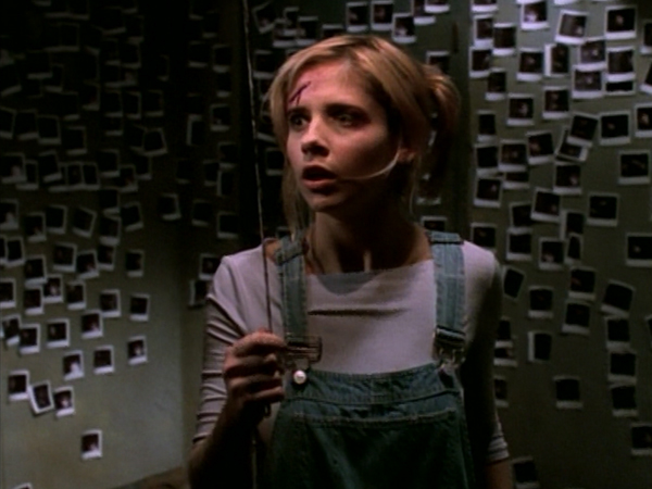 Buffy looks shocked as she stands in a room covered in photographs of her mother.