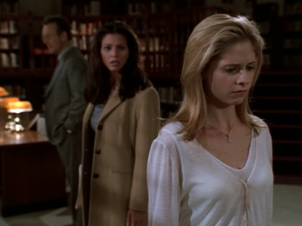 Buffy stands in the forefront of the shot with tears on her face. Cordelia stands behind her, and Giles behind them both.
